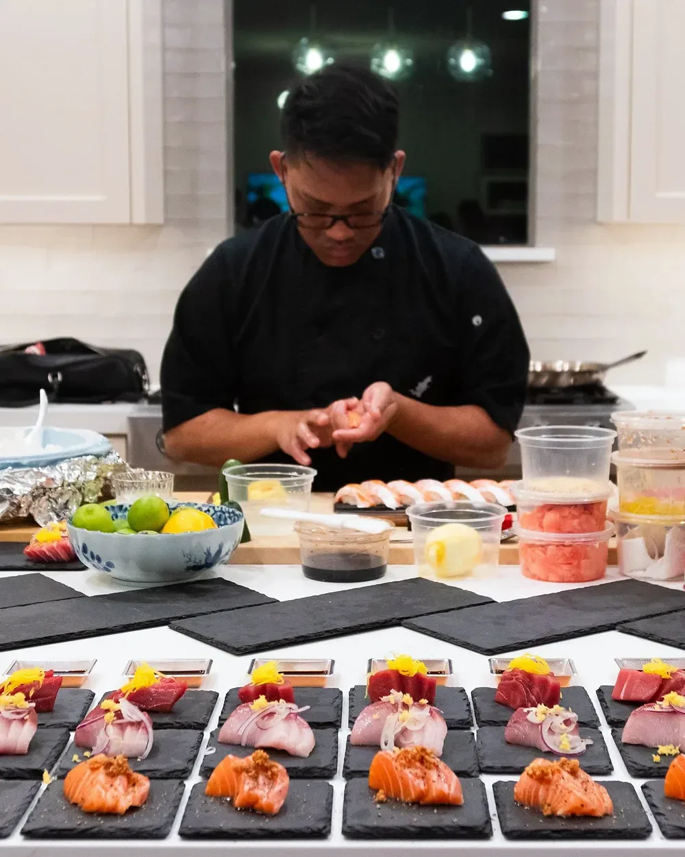 A chef plating a long line of nigiri