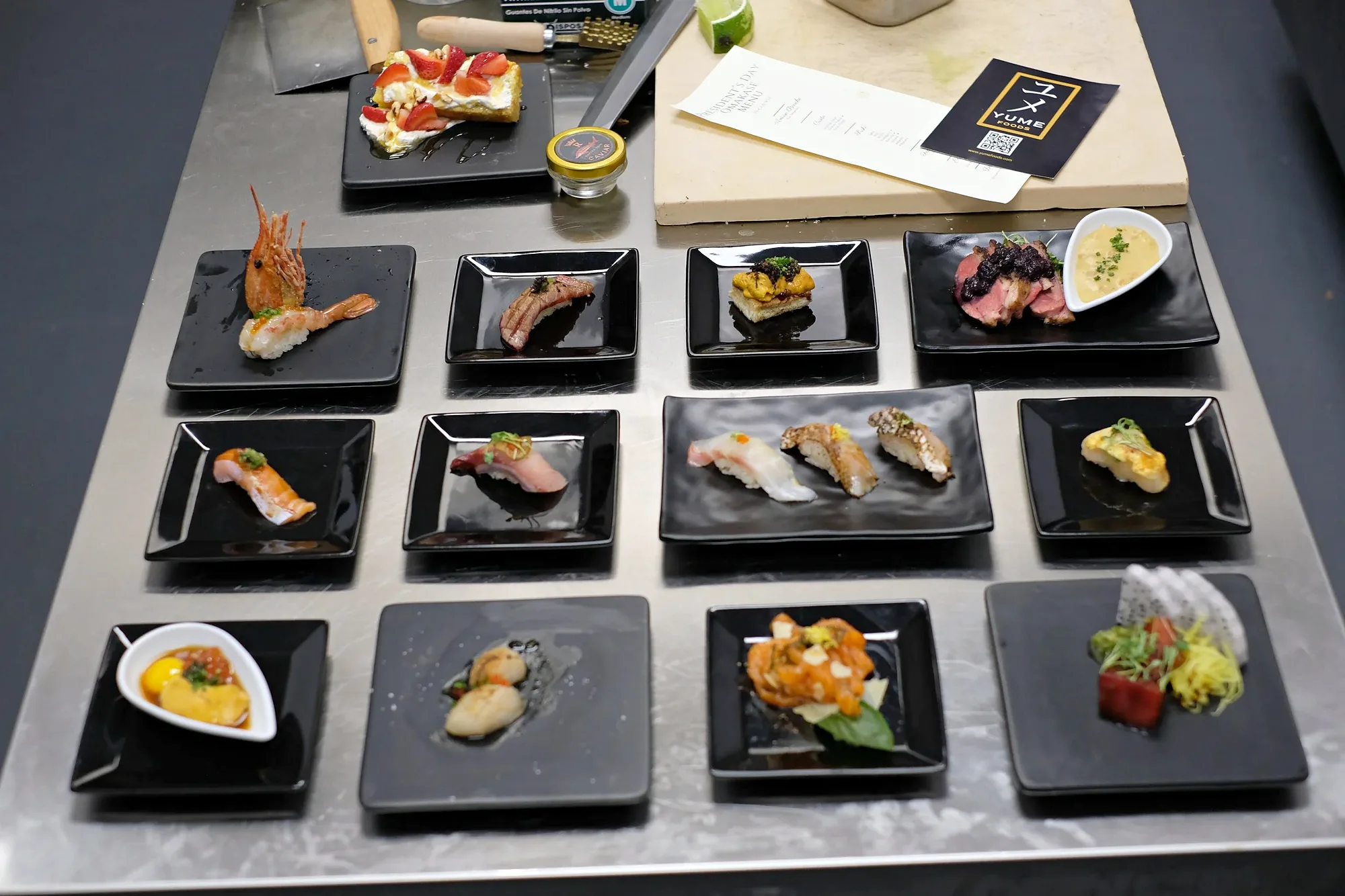 An overhead flight of nigiri, one piece to a black plate