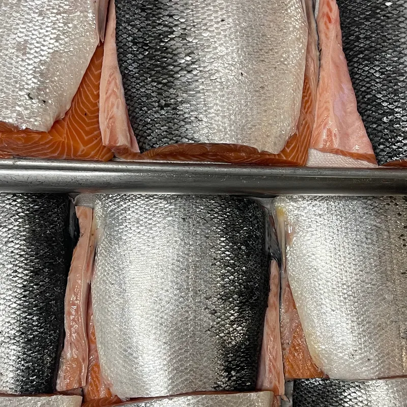 Whole salmon sides stacked on the tray before the morning break-down