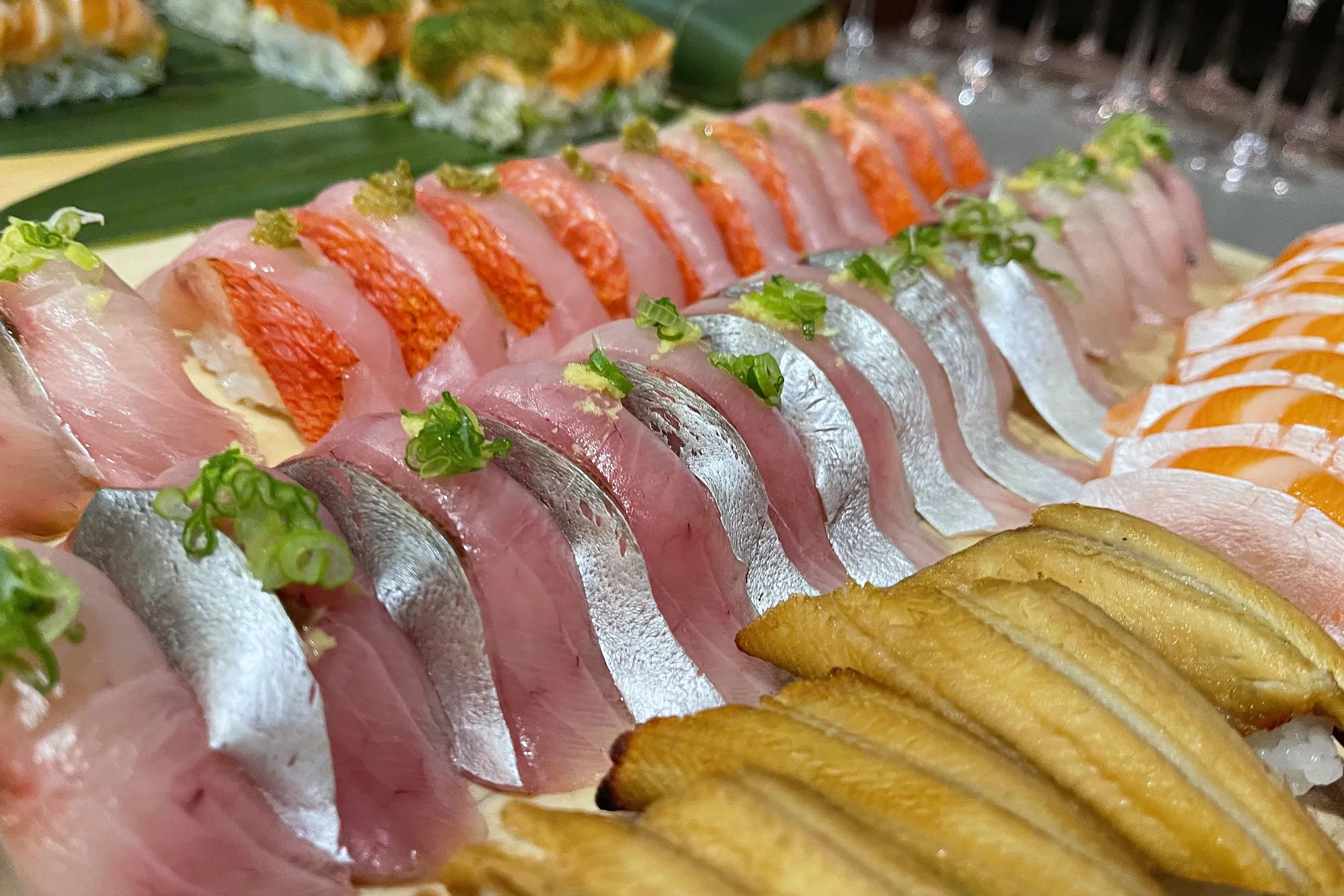 A long lineup of nigiri and sashimi along the counter
